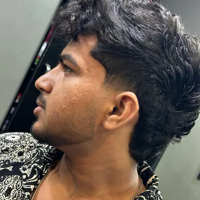 A modern mullet for curly hair. I kept the curls on top and in the back while giving the sides a sharp taper for a stylish contrast.