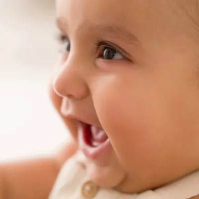The purest giggle. This tight close-up captures the absolute joy of a baby's laugh, a perfect memory from a 6-month milestone session.