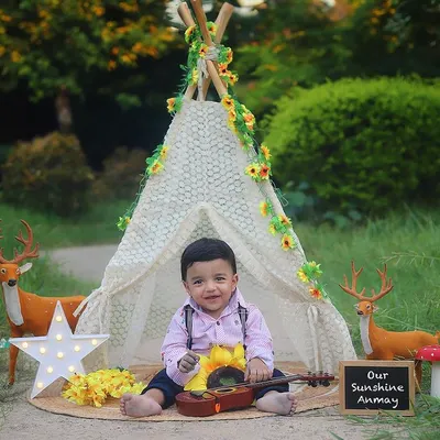 Our little musician in his outdoor boho camp! This sitter session in the park features a teepee, woodland creatures, and a tiny guitar for a truly adorable photo.