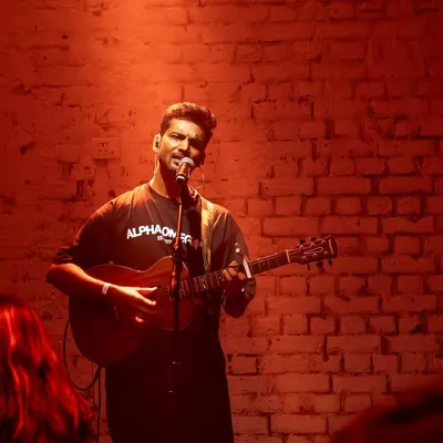 Performing a solo acoustic set at AntiSocial. The raw, intimate setting with the brick wall and red lighting created a powerful mood for an evening of indie music.