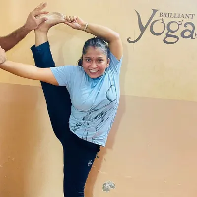 With dedicated practice and expert guidance, students can achieve remarkable flexibility and strength. Here, a student works on the standing splits, a testament to her hard work.