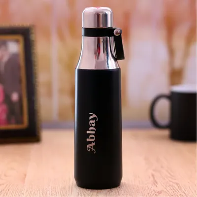 A sleek and modern personalized bottle in black and silver. I can engrave any name, like "Abhay" shown here, making it a stylish and personal accessory for the gym or office.