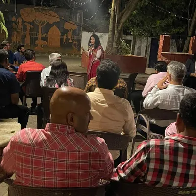 Hosting an evening event requires a different kind of energy. Here I am addressing an audience in a more informal, outdoor setting, creating a warm and engaging atmosphere.