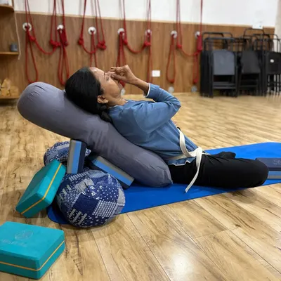 Here, a student practices Nadi Shodhana (alternate nostril breathing) while in a supported reclining pose. This combination of pranayama and restorative yoga is incredibly effective for calming the nervous system and reducing anxiety.