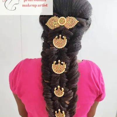 A classic South Indian bridal hairstyle featuring a thick fishtail braid. The braid is adorned with traditional temple-style hair jewels, which is a popular choice for muhurtham ceremonies.