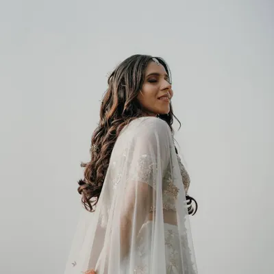 A beautiful solo portrait of the bride-to-be during her pre-wedding shoot. Her elegant white lehenga with a cape flows in the breeze, creating a dreamy and ethereal look.