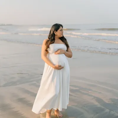 Standing by the ocean, carrying a world of dreams within. This solo beach portrait is all about capturing the serene and powerful connection between mother and nature.