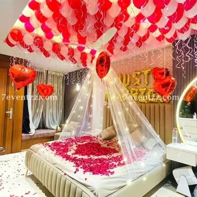 For a truly romantic first night or wedding surprise, I create setups like this one. It features a beautiful canopy over the bed with fairy lights, 'Just Married' foil balloons, and a ceiling full of red and white balloons.