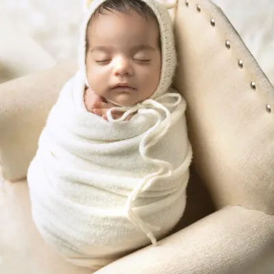 A perfectly swaddled newborn sleeping peacefully in a tiny armchair. I love using simple props like this to show just how small and precious they are. The bear-ear bonnet adds a touch of cuteness.