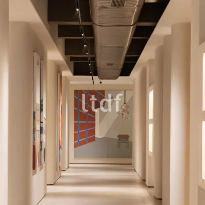 This corridor is designed to be more than a passageway; it's a spatial narrative in motion. The disciplined rhythm of the columns and the contrast between raw industrial ceiling elements and curated art invites both reflection and interaction.