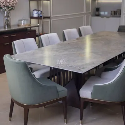 The Aurum Dining Set, featured in a Delhi NCR residence. This table boasts a solid wood top with softly rounded edges, complemented by ergonomically designed chairs in a luxurious two-tone fabric of sage green and neutral grey.