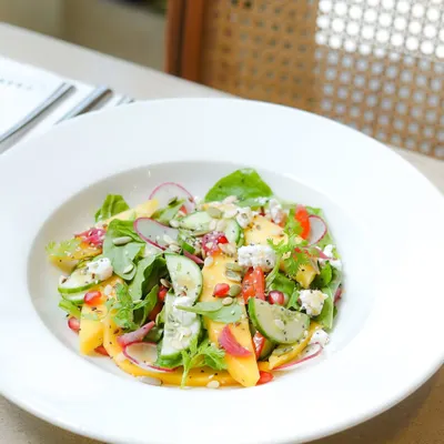 Our seasonal baby spinach and Alphonso mango salad. This refreshing dish combines sweet mango, crisp cucumber, and creamy feta, capturing the taste of summer in a bowl.