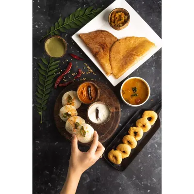 A complete South Indian breakfast spread, styled and shot for Double Tree by Hilton. This top-down flatlay captures the variety of the meal, from crispy dosas to savory sambar, perfect for a hotel menu.