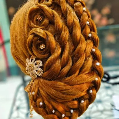 An intricate braided updo with rose details and pearl accents, created by a student on a mannequin head.