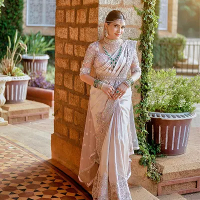 A full view of a breathtaking custom ensemble. We designed the 3D floral embroidered blouse, the intricately worked saree border, and the delicate sheer veil to create this cohesive and regal look for the bride.