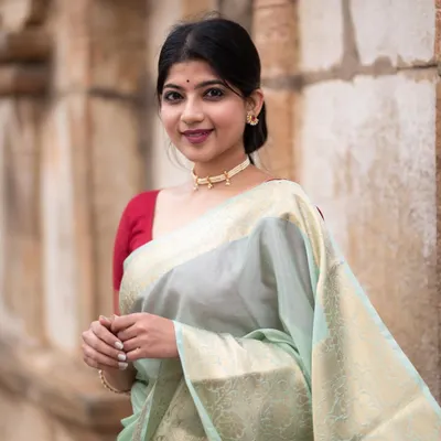A portrait in a seafoam green Banarasi silk saree, taken at a beautiful temple. The soft morning light and serene expression create a peaceful and divine mood.
