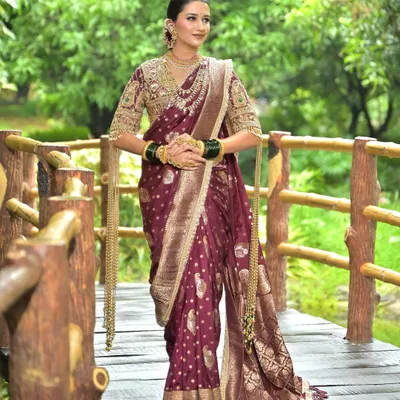 A regal Maharashtrian bride in a deep magenta Nauvari saree, featuring a classic bun, gold jewellery, and green bangles.