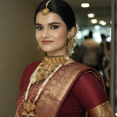 This is the epitome of South Indian bridal glam. I created a flawless matte base, defined the eyes with classic liner, and paired it with a rich lip color to complement the maroon silk saree and heavy temple jewelry.