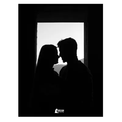 A silhouette of the couple against a window, framed by darkness. This minimalist and artistic shot focuses purely on their connection and the outline of their love.