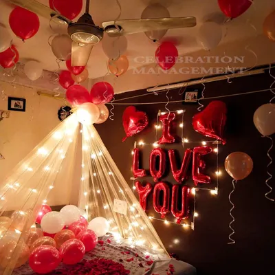 A perfect blend of cozy and romantic, this bed canopy is created with sheer fabric and fairy lights. The setup is completed with "I LOVE YOU" foil balloons and a mix of red and white balloons for a classic expression of love.