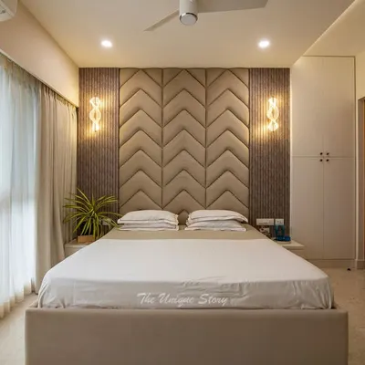 This modern master bedroom is a study in texture and tranquility. We designed a custom chevron-patterned upholstered headboard as the centerpiece, flanked by elegant wall sconces and fluted wall panels to create a sophisticated and restful retreat.