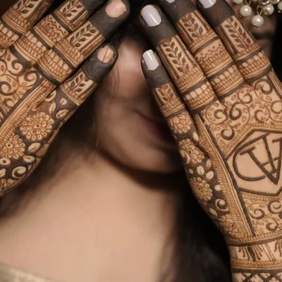 A simple yet elegant way to personalize your mehendi. This design features the couple's initials "AV" enclosed in a geometric crest on the back of the hands.
