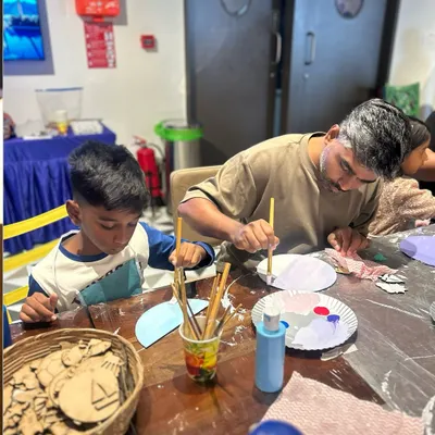 A father and son working together on a painting project during our Father's Day workshop. It's moments like these that make art so meaningful.
