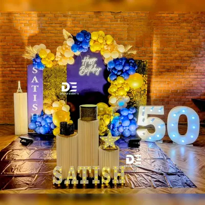 A bold and stylish 50th birthday celebration with a royal blue and gold theme, featuring a shimmer wall, large marquee numbers, and personalized light-up letters.