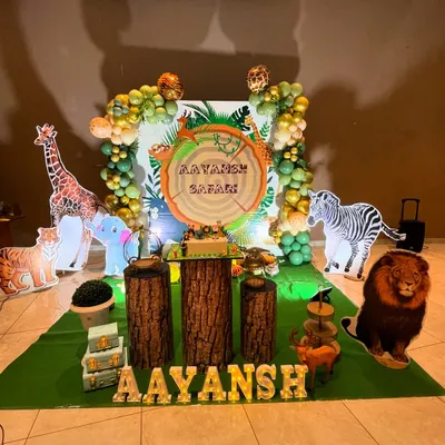 A fantastic jungle safari theme for Aayansh's birthday. The setup includes a giraffe, zebra, and lion, with a custom 'Aayansh Safari' backdrop and marquee letters.
