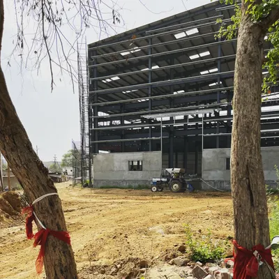 A factory building under construction, revealing its massive steel frame. We apply the same principles of structural clarity and functional design to our industrial projects as we do to our residences.
