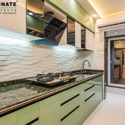 A modern kitchen in Seawoods featuring mint green handleless cabinets and a 3D textured white backsplash. The design includes a chimney hood and mirrored overhead cabinets, combining aesthetics with practicality.