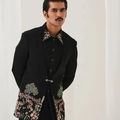 From our Nazaakat collection, this black bandhgala features intricate floral embroidery on the hem and a detailed embroidered collar. It's a subtle yet powerful statement piece for any formal occasion.
