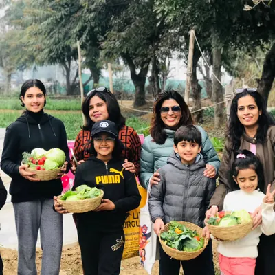 A happy group of children and adults showing off their baskets filled with a colorful assortment of freshly harvested vegetables.