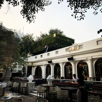 A wide view of the outdoor dining area at Diablo restaurant in Mehrauli. Our landscaping work, including the green walls and large trees, helps create a sophisticated, open-air ambiance.