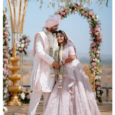 A moment of quiet connection amidst the grandeur of the wedding ceremony. The couple stands before a beautiful floral arch, ready to begin their new life together.