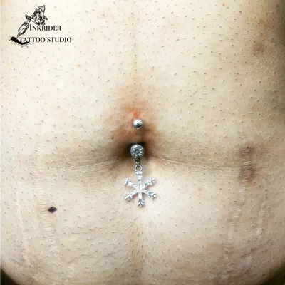 A festive navel piercing with a dangling snowflake charm, perfect for adding a unique touch. I have a wide selection of jewelry, including crystal and charm barbells.