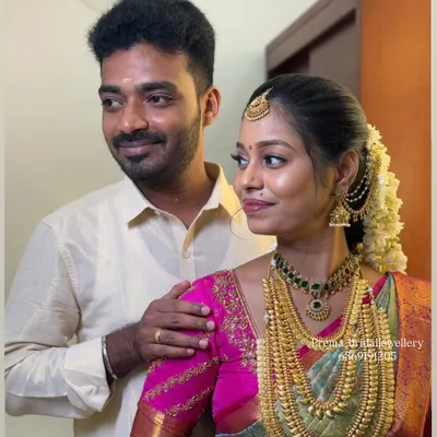 A beautiful moment between the bride and groom. The bride is wearing a stunning layered temple jewellery set that complements her pink and green saree.