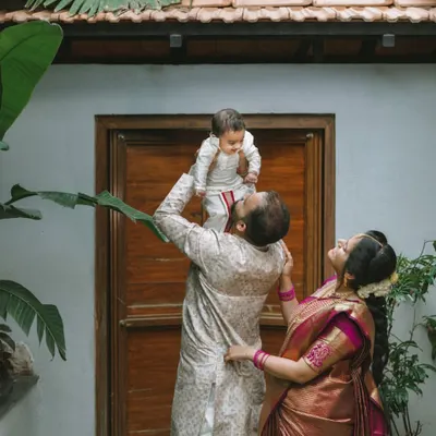 A candid moment of pure happiness as a father lifts his child up. The mother looks on with a smile, perfectly capturing the love and connection of this new family.
