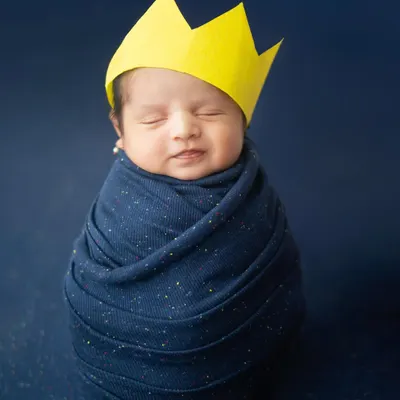 Our little king, wrapped snugly and dreaming big. This simple yet royal setup with a paper crown highlights the precious innocence of a newborn.