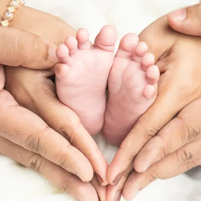 The tiniest feet held in the safest hands. This heart shape formed by the parents' hands is a beautiful way to symbolize their love and protection for their new baby.