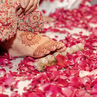 Sometimes the smallest details tell the biggest stories. A bride's feet, adorned with intricate mehendi and toe rings, step onto a bed of soft rose petals. It’s a poetic frame that signifies the beginning of her new journey.