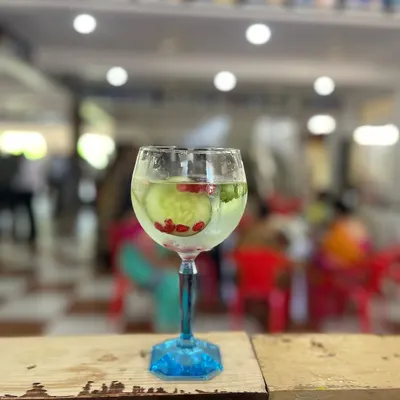 A refreshing Gin and Tonic, perfectly presented in a balloon glass. This classic drink is garnished with a ribbon of cucumber and pomegranate seeds, showing our attention to detail.