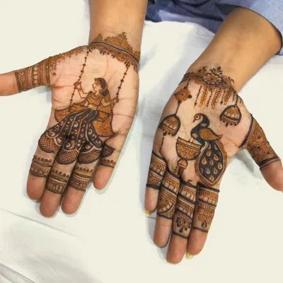 This design for the Sawan season features a woman on a swing on one palm and a peacock with jhumkas on the other. The distinct themes on each hand tell a beautiful story of monsoon celebrations.