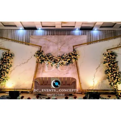 A wide-angle view of a contemporary reception stage featuring a striking white marble-effect backdrop. The geometric gold frames and cascading florals add a touch of modern luxury, perfect for a stylish wedding.