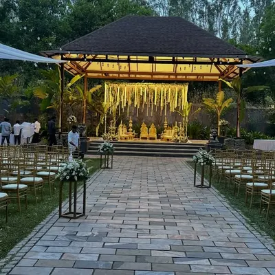 This wide-angle view shows a complete outdoor wedding setup at a resort. We arranged the guest seating along a stone pathway leading to the beautifully lit mandap, with white drapes overhead to create an elegant, open-air wedding venue.