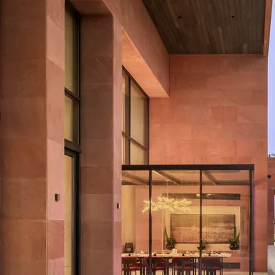 The exterior of the Elevate Clubhouse in Gurugram, where a glass-encased dining room creates a seamless connection between the interior and the landscaped outdoors. The use of red sandstone and large transparent surfaces establishes a modern yet warm architectural presence.