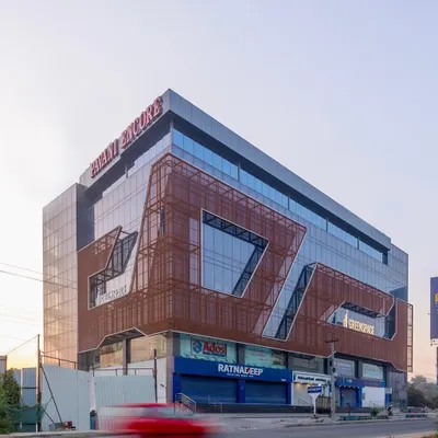 The facade of this commercial building is fluidic and minimalistic, using glass and expanded metal as primary materials. This lends a futuristic touch to the built form, which houses retail on the ground floor and offices above.