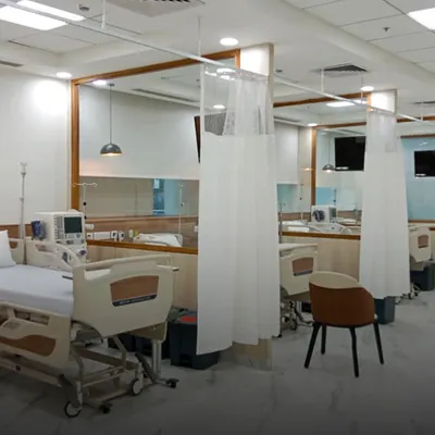A view of the patient recovery area at Gangaram Hospital. The design uses warm wood tones and privacy curtains to create a space that is both functional for medical staff and comforting for patients.