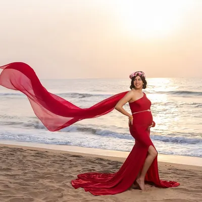 The power and grace of motherhood, captured at sunrise. The flowing red gown catches the sea breeze perfectly, creating a moment of pure, effortless elegance on the beach.
