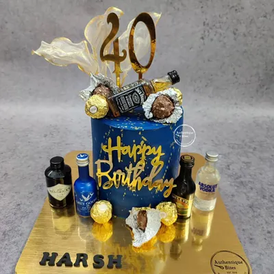 A loaded liquor and chocolate cake for a 40th birthday. This non-fondant blue and gold cake is topped with miniature alcohol bottles and Ferrero Rocher chocolates.